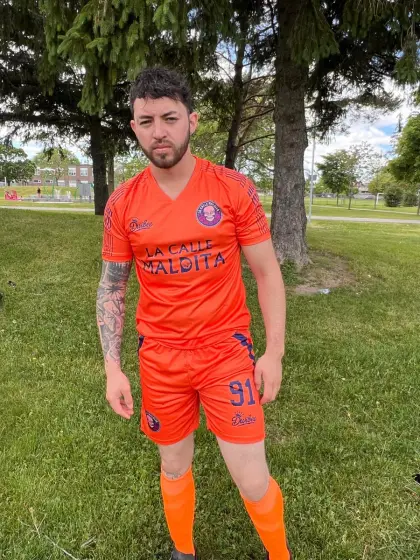Adrián Guerra, portero de La Calle Maldita, con el uniforme naranja en una cancha de pasto